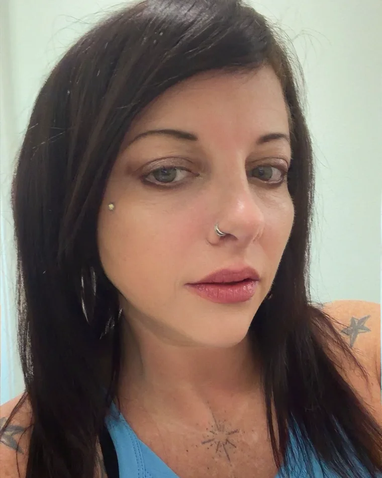 Sarah, a professional hair stylist with long dark hair, looking toward the camera.