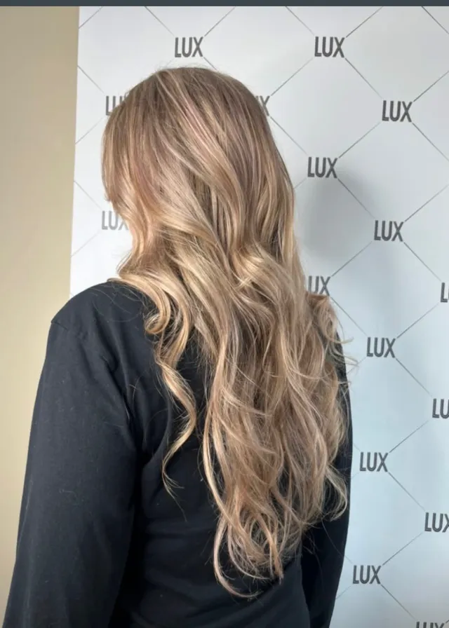 Soft beige-blonde dimensional color styled in long waves.