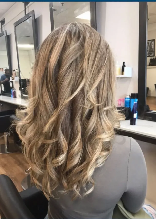 Long warm-blonde highlights styled in layered curls.