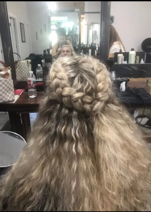 Textured half-up hairstyle finished with braided rosettes.