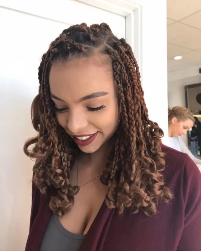 Long copper-toned braids with curled ends.