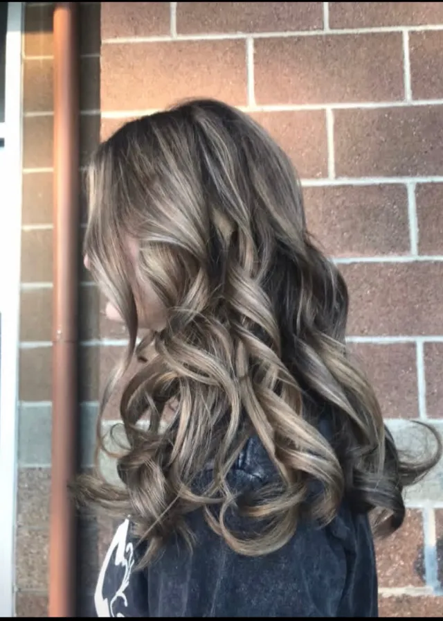 Cool brunette hair with ash-blonde dimensional ribbons and a curled finish.