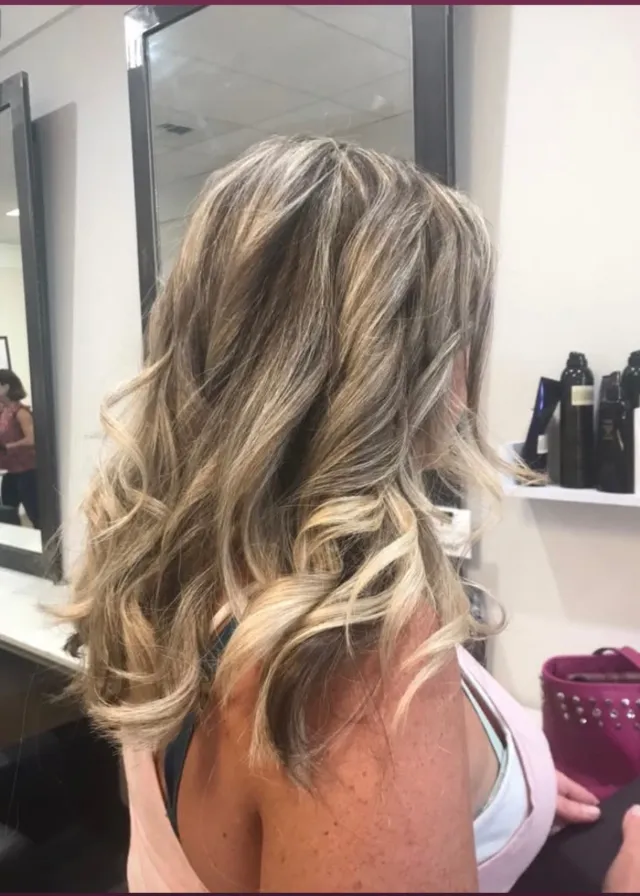 Brunette-to-blonde highlighted hair in shoulder-length waves.