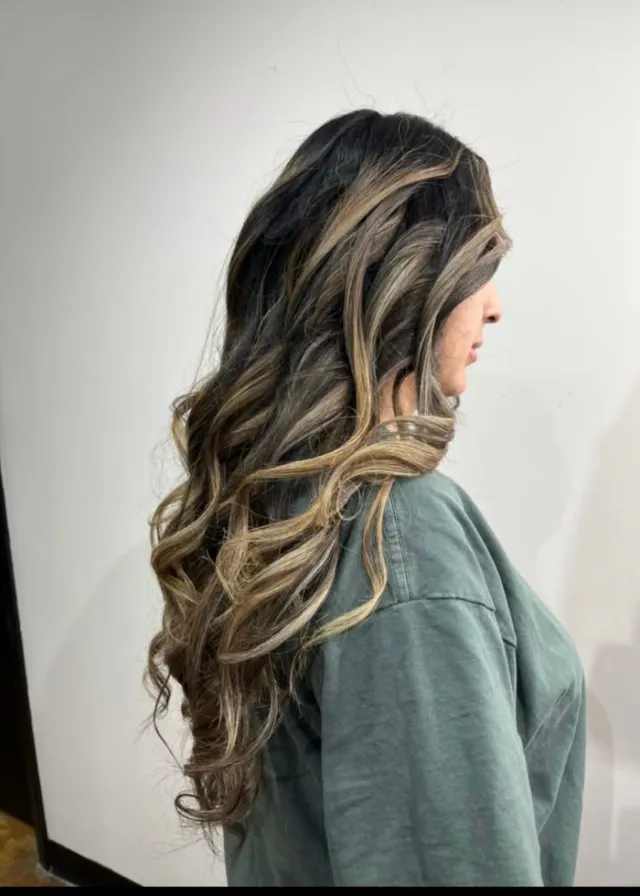Dark brunette hair with caramel and blonde face-framing highlights.
