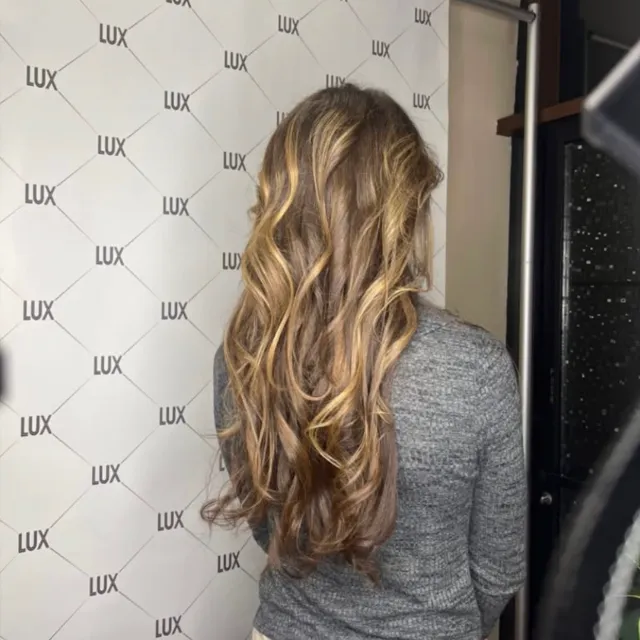 Warm honey-blonde dimensional highlights on wavy hair.