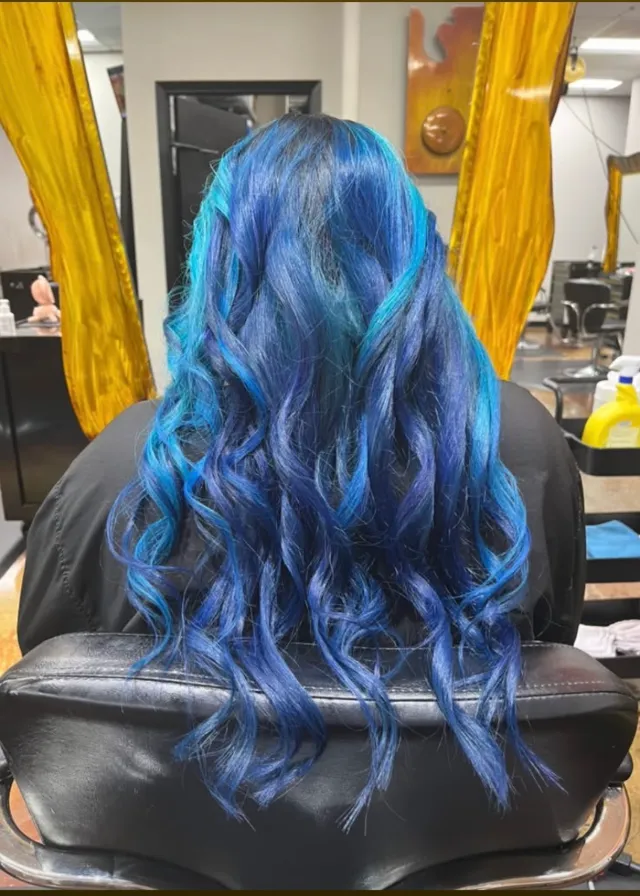 Blue toned hair with darker roots styled in loose waves.