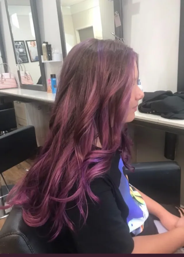 Muted plum and wine-toned hair color with layered movement.