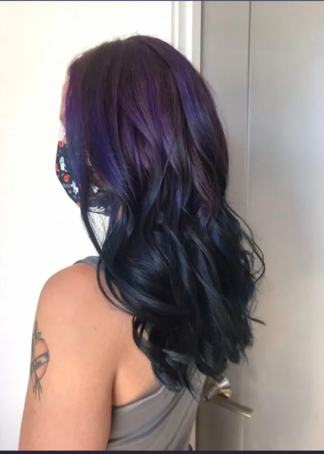 Deep dark hair fading into purple lengths with soft curls.