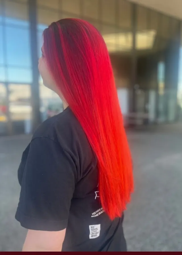 Long straight hair with a dark root and saturated red-to-orange vivid color.